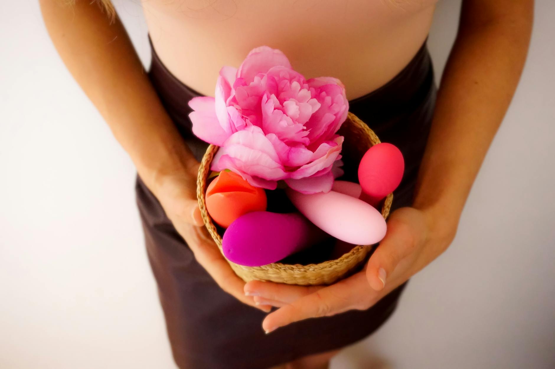 Colorful vibrators and personal wellness items arranged in a basket, symbolizing postpartum self-care and pleasure recovery